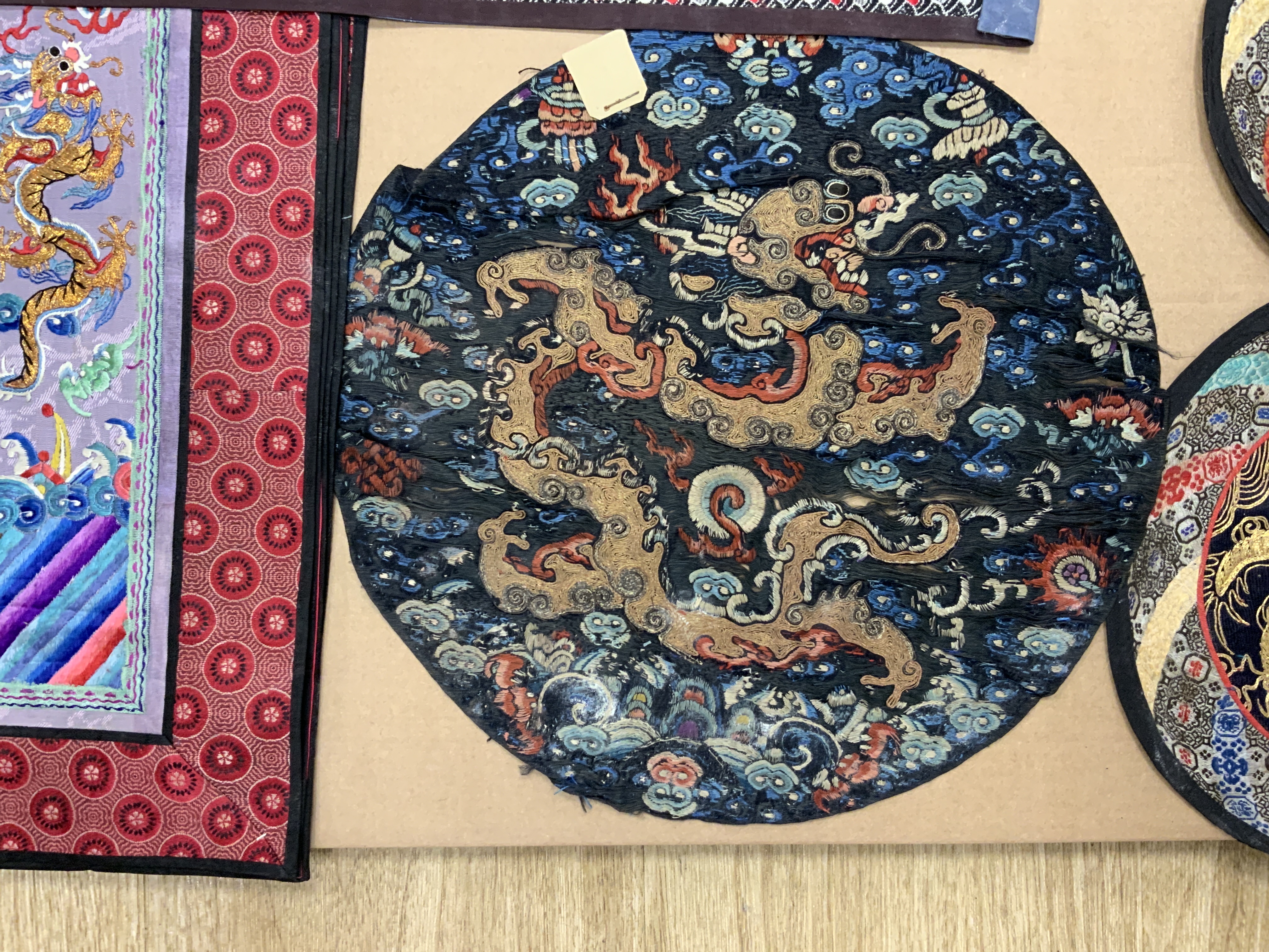 A group of five Chinese gold thread and polychrome silk embroidered circular mats, embroidered with central gold thread dragons four bordered in silk brocade, together with a set of four rectangular similar embroidered g